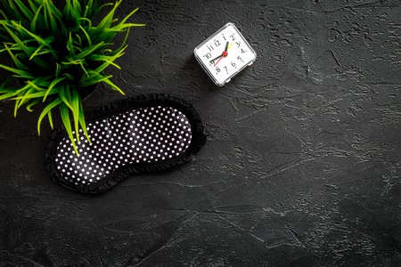 Sound sleep concept. Sleep mask, plant, alarm clock on black background top view copyspaceの写真素材
