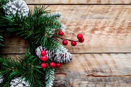 Christmas wreath woven of spruce branches with red berries on light wooden background top view closeup.の写真素材