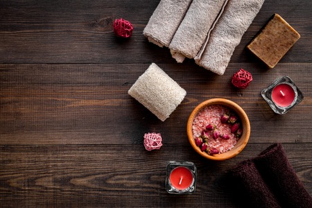 Floral foot spa with rose. Candles, salt, sponge, soap, buds on dark wooden background top view copyspaceの写真素材