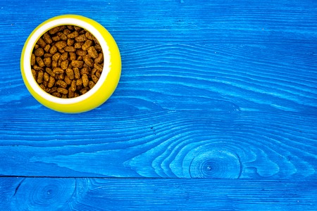 Pet food in bowl on blue wooden background top view.の写真素材
