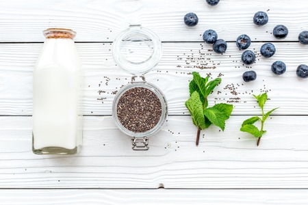 Eat chia seeds for breakfast with yogurt, blueberry and mint. White wooden background top view