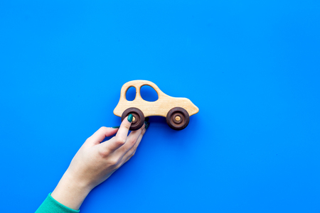 Cute wooden handmade toys for newborn. Hand hold car toy on blue background top view copyspaceの写真素材