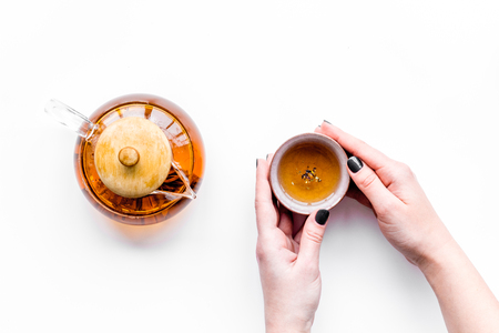 Drink tea. Hand hold cup near tea pot on white background top view copyspaceの写真素材