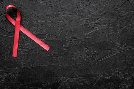 Red ribbon for HIV, AIDS, substance-abuse and anorexia awareness on black background top view.の写真素材