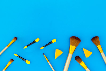 Set of brushes for makeup and eyeshadow applicator on blue background top view.