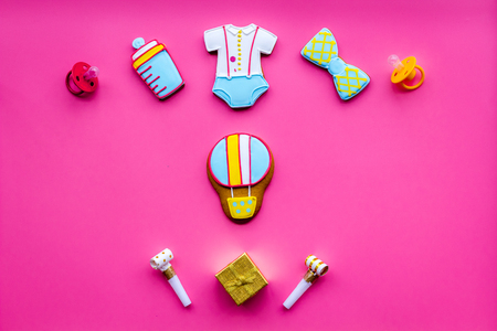 Celebrate birthday of a little baby. Cookies in shape of accesssories for child and gift box on pink background top view copy spaceの写真素材