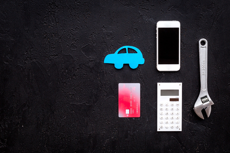 Cost of car repair. Automobile service. Car silhouette, wrench, cell phone, bank card on black backgound top view space for textの写真素材