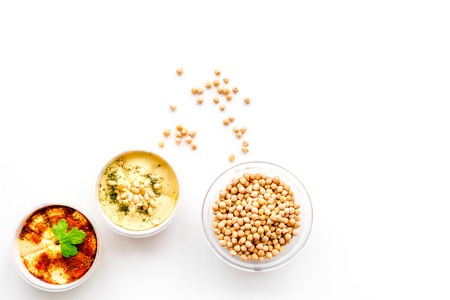 Middle Eastern cuisine. Bowls with hummus and chickpeas on white background top view.