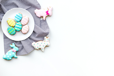 Easter background. Cookies in shape of easter bunny and easter eggs. White background top view space...