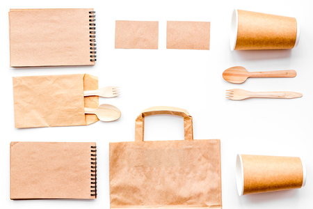 Disposable tableware. Paper cup, spoon, fork near brown paper bag and notebook top view copy space mock up.の写真素材