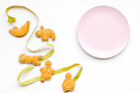 Sport and healthy diet for slimming. Plate and cookies in shape of yoga asans on white background top view.の写真素材
