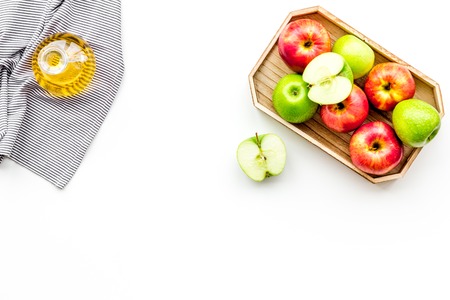 Apple cider vinegar in bottle among fresh apples on white background top view.の写真素材