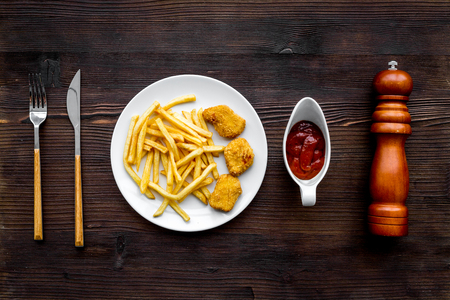 French fries and chicken nuggets with sauces on dark wooden background top viewの写真素材
