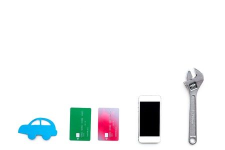 Search car service online. Mobile pay. Car silhouette, wrench, cell phone, bank card on white backgound top view copy spaceの写真素材