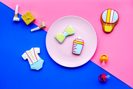 Celebrate birthday of a little baby. Cookies in shape of accesssories for child on pink and blue background top view.の写真素材