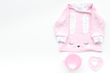 Cute pink baby clothes for girl. Shirt, toy, bottle on white background top view copy spaceの写真素材