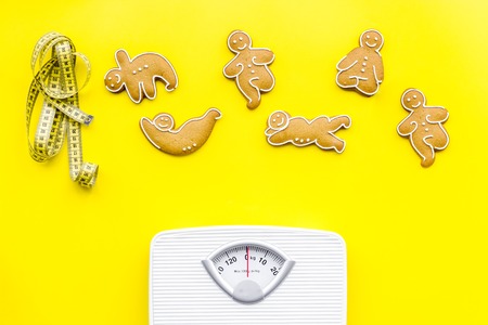 Ways for lose weight. Sport. Cookies in shape of yoga asans near scale and measuring tape on bright...