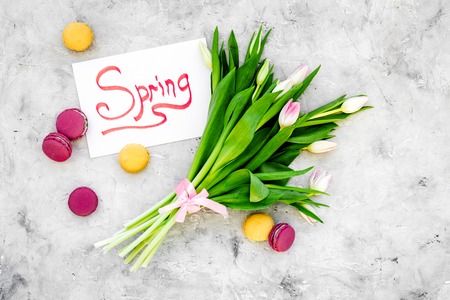Spring mood. Tulips and sweets macarons near spring hand lettering on grey background top view.の写真素材