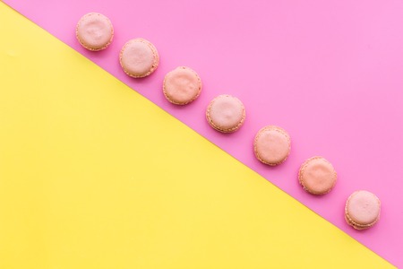 Macarons dessert. Pattern on yellow and pink pastel background top view.の写真素材