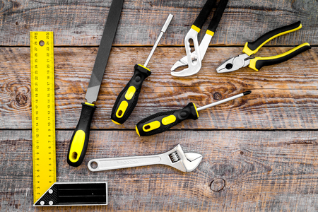 Repair tool kit. File, hummer, corner ruler on rustic wooden background top view pattern copy space