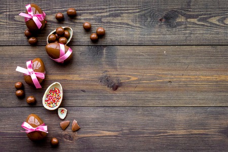 Easter composition. Easter sweet gift. Chocolate eggs near cookies in shape of Easter bunny on dark wooden background top view space for textの写真素材