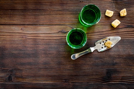 Traditions of drinking absinthe. Special spoon and sugar cubes near shots on dark wooden background top view.の写真素材