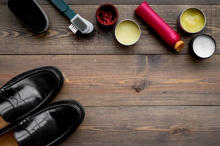 Shoe polish, brushes, wax near black shiny leather shoes on dark wooden background top view copy spaceの写真素材