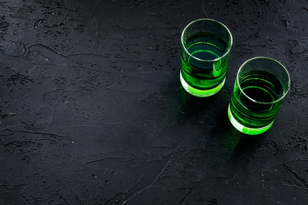 Absinthe shots on black background top view.