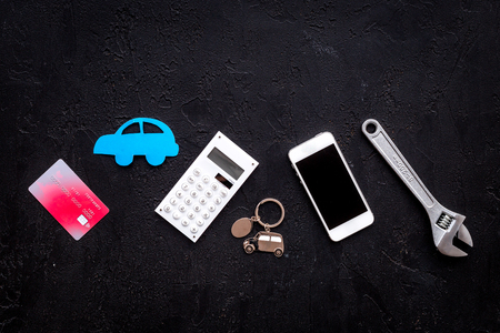 Cost of car repair. Automobile service. Car silhouette, wrench, cell phone, bank card on black backgound top view.の写真素材