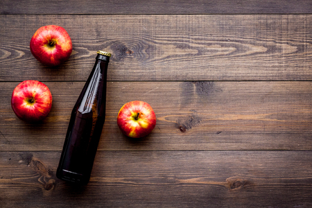 Apple cider. Low-alcoholic beveradge in dark bottle on dark wooden background top view.の写真素材