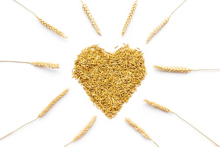 Raw oats in shape of heart on white background top viewの写真素材