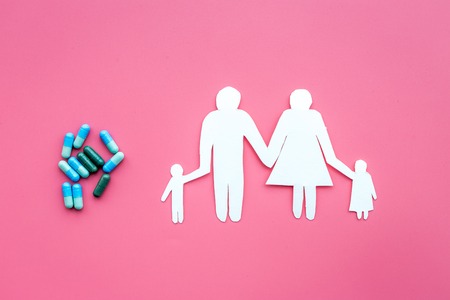 Prevention of diseases. Medicine for family health. Color pills near silhouette of family on pink background top view.の写真素材