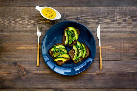 Idea for a healthy and nutritious breakfast. Plate with avocado toast with wholegrain bread on dark wooden background top view.の写真素材