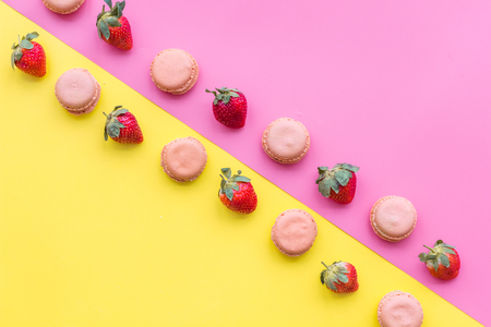 Fresh ripe strawberry. Pattern with sweets macarons on yellow and pink pastel background top view.の写真素材