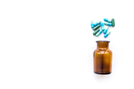 Color pills spilling out of a pill bottle on white background top view.の写真素材