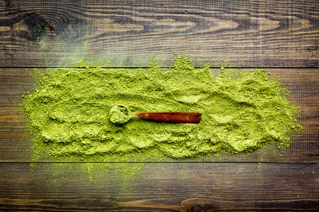Scattered matcha powder tea on dark wooden background top viewの写真素材