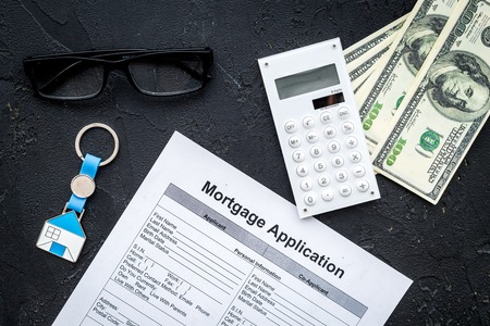 Housing loan. Draw up a mortgage. Mortgage application near keychain in shape of house and money on black background top viewの写真素材