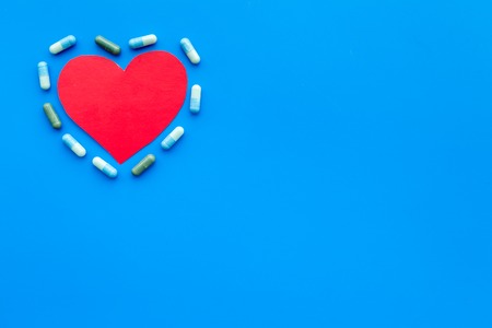 Vitamins of drugs for heart. Color pills near heart sign on blue background top view.の写真素材