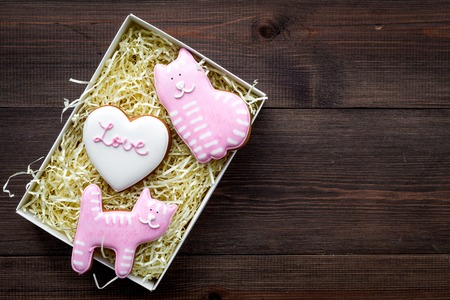 Valentine's Day candy. Heart shaped cookie with lettering Love and kitty on dark wooden background top view.の写真素材