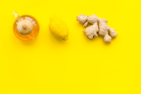 Warming tea with lemon and ginger. Cup, teapot, ginger root on yellow background top view.の写真素材