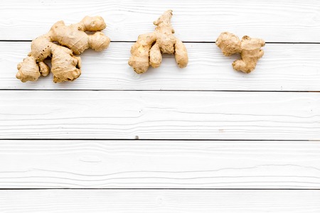 Whole ginger roots on white wooden background top view.の写真素材