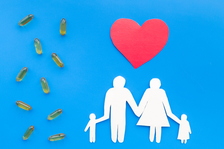 Prevention of diseases. Medicine for family health. Color pills near silhouette of family on blue background top view.の写真素材