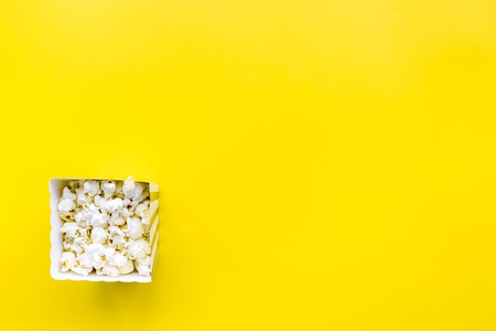 Popcorn in paper bag on yellow background top view.の写真素材