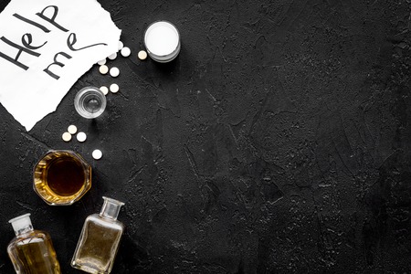 Treat alcohol dependence. Words Help me near glasses, bottles and pills on black background top view.の写真素材
