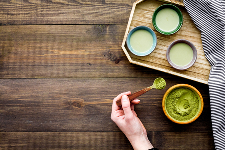 Japanise tea ceremony with matcha tea. Bowl with powder and cups with beverage on tablecloth on dark wooden background top view.の写真素材