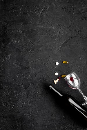 Alocohol abuse and alcoholism treatment concept. Glasses, bottles and medcine pills on black background top view.の写真素材