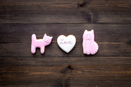 Valentines Day candy. Heart shaped cookie with lettering Love and kitty on dark wooden background top view space for textの写真素材