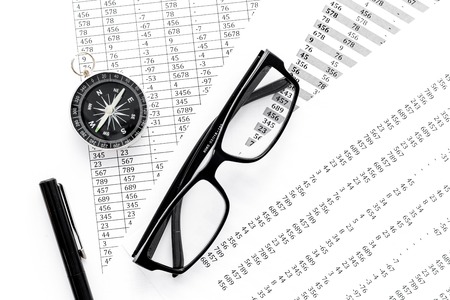 Business development concept. Direction. Compass near documents, glasses, pen on light background...