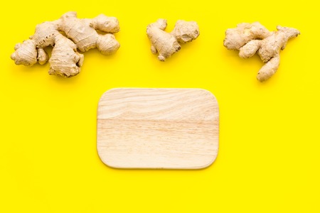Whole and sliced ginger roots, cutting board on yellow background top view.の写真素材