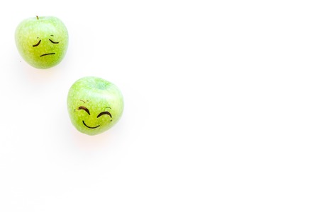 Basic emotions concept. Happy smile and sad grimace drawn on apple. White background top view copy spaceの写真素材